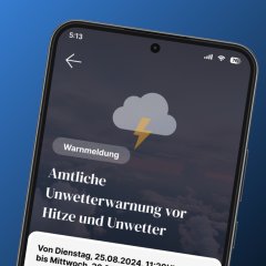 Smartphone zeigt in der FRED-App eine amtliche Unwetterwarnung mit Wetterinformationen und Hinweisen zu Hitze und Gewitter.