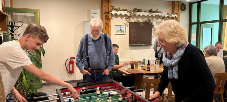 Jugendliche und Erwachsene spielen gemeinsam Tischfußball.