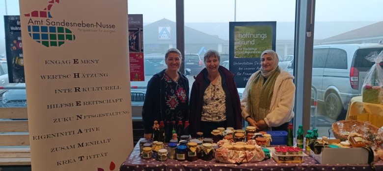 Drei Frauen stehen an einem Verkaufsstand mit selbstgemachten Produkten