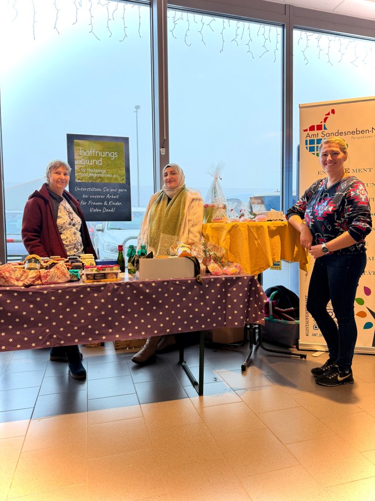 Stand mit selbstgemachten Produkten, drei Frauen posieren davor.