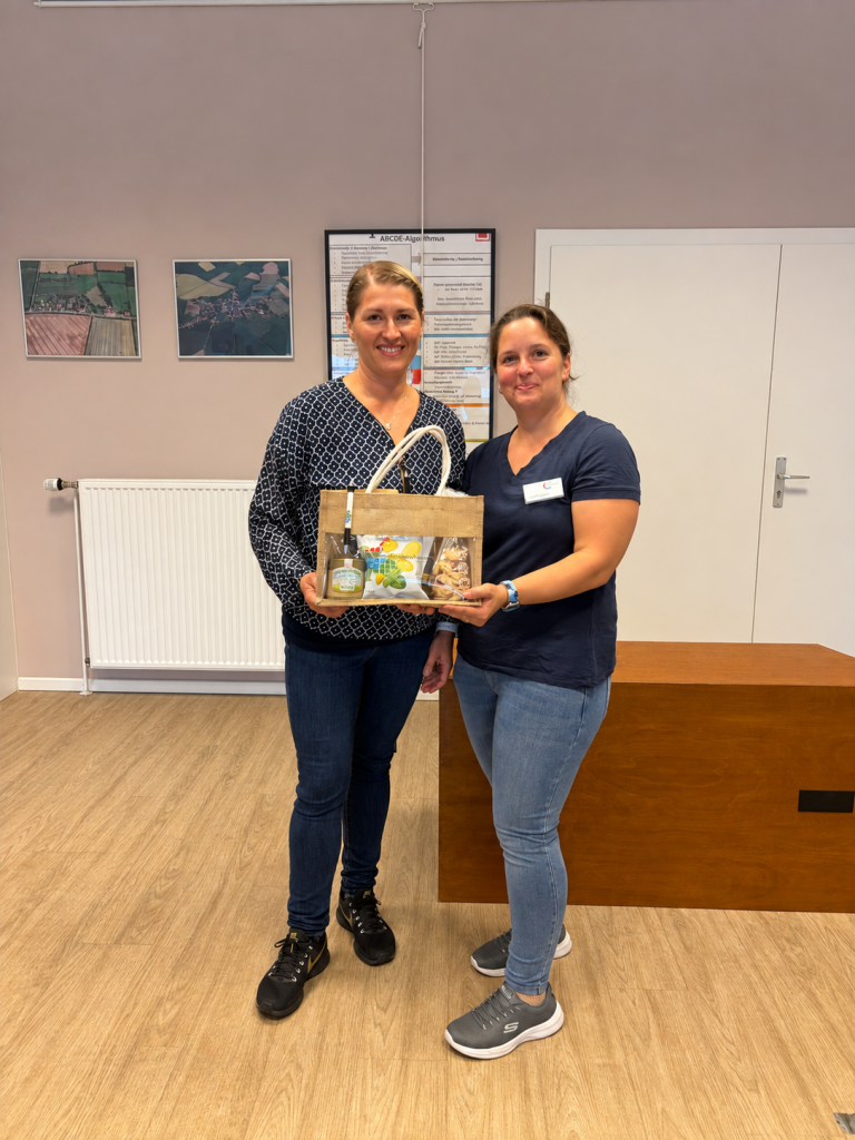 Zwei Frauen bei der Übergabe eines Präsentkorbs.