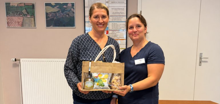 Zwei Frauen bei der Übergabe eines Präsentkorbs.