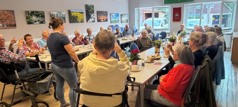 Gesellige Runde mit älteren Menschen an gedeckten Tischen bei einer gemeinsamen Veranstaltung.