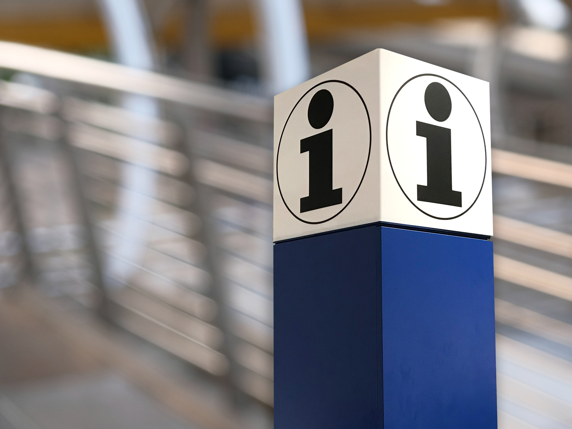 Informationssymbol auf einer blau-weißen Säule mit einem schwarzen „i“ in einem Kreis, das auf eine Informationsstelle hinweist.