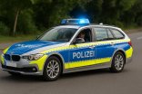 Deutsches Polizeiauto mit eingeschaltetem Blaulicht auf einer Straße.