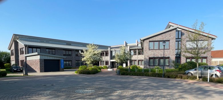 Das Bild zeigt das Regionalzentrum des Amts Sandesneben-Nusse. Vor dem Gebäude befindet sich ein großzügiger, kreisförmig gepflasterter Platz mit Grünanlagen und Parkplätzen. Das Regionalzentrum beherbergt zentrale Verwaltungsbereiche des Amts.