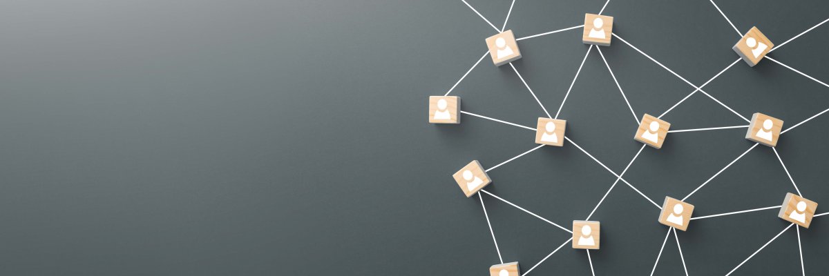 Symbolische Darstellung eines Netzwerks mit verbundenen Holzblöcken, auf denen stilisierte Personen abgebildet sind – Sinnbild für Kommunikation und Zusammenarbeit.